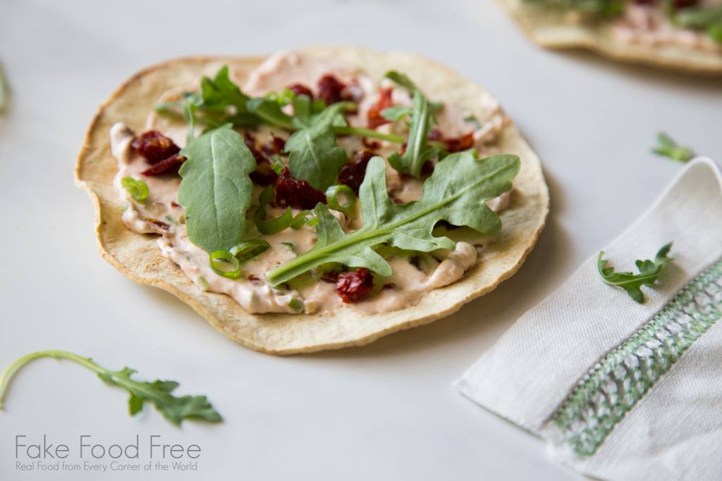 Tostadas topped with sundried tomato spread and arugula | Recipe at FakeFoodFree.com